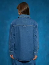 Sobrecamisa de denim azul con cuello camisero, cierre frontal con botones a presión, mangas largas con puños abotonados, dos bolsillos con solapa abotonada en el pecho y corte recto.