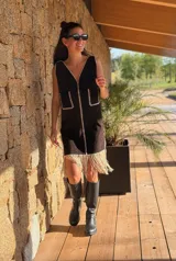 Vestido corto marrón de gamuza sintética, sin mangas, con escote en V y detalle de flecos en el ruedo. Presenta apliques bordados en el frente y laterales.