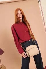 Bandolera de cuero sintético color beige, con diseño compacto y elegante. Cuenta con un bolsillo frontal con cierre y un compartimento principal con cierre. La correa es regulable.