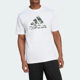 Remera de algodón blanca de manga corta, con cuello redondo y un gran logo Badge of Sport de Adidas estampado en el centro del pecho con diseño de camuflaje en tonos verde militar, gris y beige.