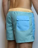 Short de baño celeste con cintura elastizada color salmón y cordón de ajuste blanco.