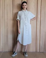 Vestido camisero midi de lino color celeste claro, con cuello clásico, mangas cortas y cierre frontal con botones.