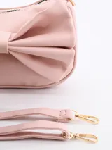 Cartera de mano rosada con moño grande decorativo en el frente y cierre superior con cremallera.