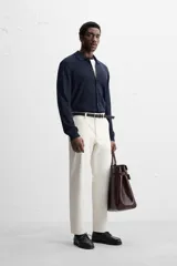 Pantalón chino negro slim fit confeccionado en tejido técnico de secado rápido. Cuenta con bolsillos frontales y traseros de vivo. Cierre frontal con cremallera y botón.
