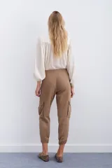 Pantalón de corderoy gris, de corte holgado, con elástico en la cintura, cierre y botón. Tiene bolsillos aplicados en el delantero y puños con elástico interno.