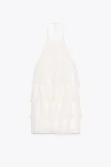 Minivestido blanco con cuello halter ajustable con lazos y falda escalonada con volantes. Espalda descubierta.