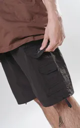 Bermuda cargo negra de nylon y spandex, con calce relax-fit, cintura elástica, cordón de ajuste y bolsillos delanteros con fuelle.