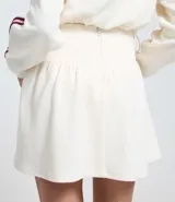 Short pollera corto de malla waffle color blanco, con cintura ancha en V y cierre de cremallera en la espalda. Presenta rayas contrastantes en los laterales.