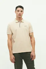 Polo color beige con textura, corte regular, logo estampado en el pecho y mangas cortas con ribete blanco.