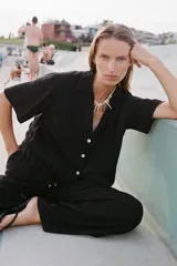 Pantalón negro de tiro alto con cintura elástica ajustable con cordones, bolsillos delanteros y pernera ancha.