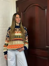 Sweater de lana merino con cuello redondo y diseño con motivos geométricos en tonos azul, marrón, naranja, verde y beige.