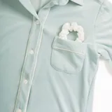 Pijama celeste de terciopelo, compuesto por una camisa de manga larga con botones y vivo blanco, bolsillo en el pecho y un pantalón recto con elástico en la cintura.