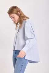 Camisa celeste con hombreras y mangas abullonadas.