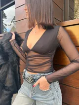 Remera negra de mangas largas confeccionada en tejido de red transparente, con escote en V y fruncido en la parte delantera.