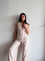 Pantalón ancho de tiro alto, color crema con estampado vertical de rayas irregulares en tono rosado/violeta. El pantalón tiene cintura elástica y corte recto y holgado.