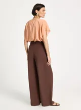 Pantalón sastrero marrón de pierna ancha, tiro alto, pretina estructurada con trabillas, pliegues frontales y cierre de cremallera.