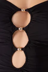 Traje de baño entero negro con escote bandeau, breteles ajustables, cortes circulares con cuentas al centro y recogidos laterales.