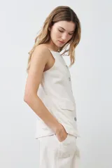 Chaleco color beige con botones de nácar, sin mangas y con bolsillos frontales.