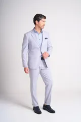 Traje de vestir celeste claro, compuesto por saco de dos botones con solapa de muesca, bolsillo de ojal en el pecho y bolsillos con solapa en los laterales, y pantalón de vestir de corte recto con ruedo arremangado.