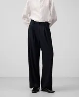 Pantalón de vestir azul marino con pinzas asimétricas, corte ancho y bolsillos de vivo en la parte trasera.