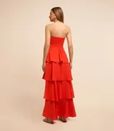 Vestido largo sin breteles, color naranja, hecho en crepé. Tiene lastex en la espalda y capas superpuestas en la pollera.