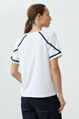 Remera blanca de algodón con escote en V y detalle de vainillas en mangas y hombros.