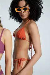 Traje de baño de dos piezas color naranja, tejido a crochet. El corpiño es triangular con tiras finas para atar en el cuello y la espalda. La bombacha es cavada con tiras finas para atar en los laterales.