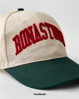 Gorra de béisbol de dos tonos, con visera curva y copa estructurada. Tiene bordado frontal en alto relieve con el texto "RONASTUDIO SOUTHAMERICAN LEAGUE".