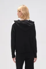 Campera negra de tejido de punto con capucha, cierre frontal y bolsillos tipo canguro. Presenta una franja blanca vertical en cada manga.