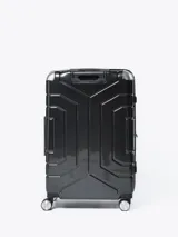 Valija rígida de viaje color negro con diseño geométrico en relieve, manija telescópica y cuatro ruedas con giro de 360°.