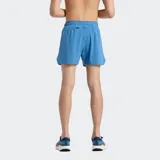 Short de running celeste con cintura elástica ajustable con cordón, slip interior integrado, tecnología de secado rápido NB DRY, bolsillo trasero con cremallera y detalles reflectantes.