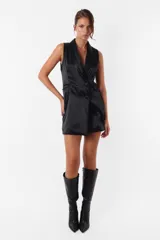 Vestido corto negro tipo blazer sin mangas, con cuello solapa, abotonadura cruzada y bolsillos ojal.