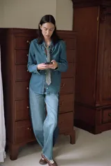 Jeans de tiro medio y corte barrel, confeccionados en denim de lavado celeste claro, con paneles laterales de denim azul oscuro a contraste. Presentan cinco bolsillos y cierre frontal con cremallera y botón.