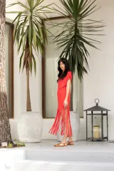 Vestido de algodón color rojo con cuello redondo y corte recto. Presenta mangas cortas y flecos en el ruedo.