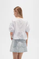 Blusa de algodón a rayas verticales color celeste y blanco, con cuello redondo, mangas cortas abullonadas y corte peplum.