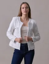Chaqueta Nanette de tejido tweed color blanco, con escote mao, abertura central y bolsillos delanteros. Presenta apliques de botones perlados en los puños y terminación desflecada.