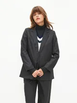 Blazer negro con finas rayas verticales blancas, solapas de muesca, cierre frontal con un botón y bolsillos laterales con solapa.