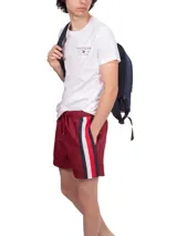 Short de baño rojo con cintura elástica ajustable con cordón y rayas verticales blancas, azul marino y rojas en el lateral.