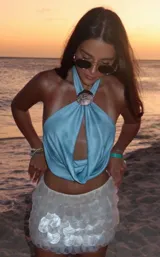 Top halter color celeste con detalle de argolla dorada en el cuello.