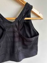 Top deportivo color marrón con textura de rayas horizontales, breteles anchos, espalda deportiva y cierre frontal con cremallera. Incluye almohadillas removibles.