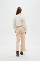 Pantalón de algodón color beige, de tiro alto, corte ancho y largo, con bolsillos frontales tipo parche.