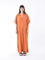 Vestido largo color naranja, con cuello camisero, mangas cortas y corte holgado.