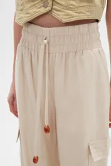 Pantalón cargo color beige de viscosa, tiro alto, corte recto y bolsillos laterales.