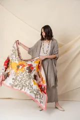 Pañuelo cuadrado de seda con estampado floral en tonos naranja, rojo, marrón y verde sobre fondo blanco.