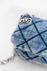 Bandolera azul de denim con diseño acolchado en forma de rombos. Tiene correa de cadena metálica y asa corta de denim.