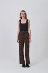 Pantalón de tiro alto, corte recto y largo, con estampado de lunares blancos sobre fondo negro.