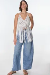 Top blanco de crochet con escote en V, tirantes finos y flecos.