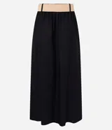 Pollera midi evasé color negro, confeccionada en viscolino, con trabillas en la cintura y cinturón de ráfia con hebilla redonda.
