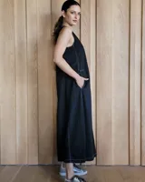 Vestido largo color crudo, sin mangas y con escote en V. Presenta aberturas laterales en el ruedo y bolsillos laterales a la altura de la cadera.