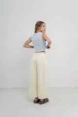 Pantalón 3/4 estilo palazzo confeccionado en denim liviano de tono amarillo pastel, tiro medio con pliegues delanteros, bolsillos delanteros y traseros aplicados, con detalle de logo metálico PEACH en la parte posterior.